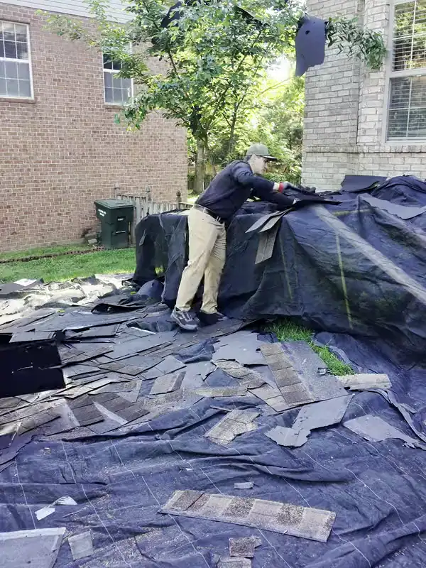 A Hisway project manager folding a tarp full of old shingles during the tear-off